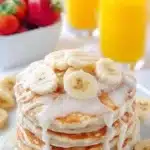 Fluffy banana pancakes topped with fresh banana slices and syrup