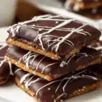 Chocolate covered graham crackers on a white plate, drizzled with chocolate.