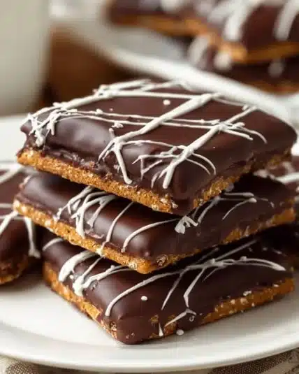 Chocolate covered graham crackers on a white plate, drizzled with chocolate.