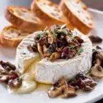 Wild Mushroom and Camembert Toasts topped with fresh herbs on a wooden board